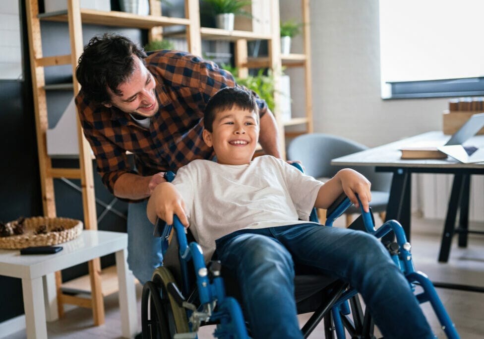 A support worker and young participant in his wheelchair sharing a laugh